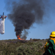 A firefighter watches as a helicopter drops water on a smoldering hillside on February 10, 2022 in Laguna Beach, California.